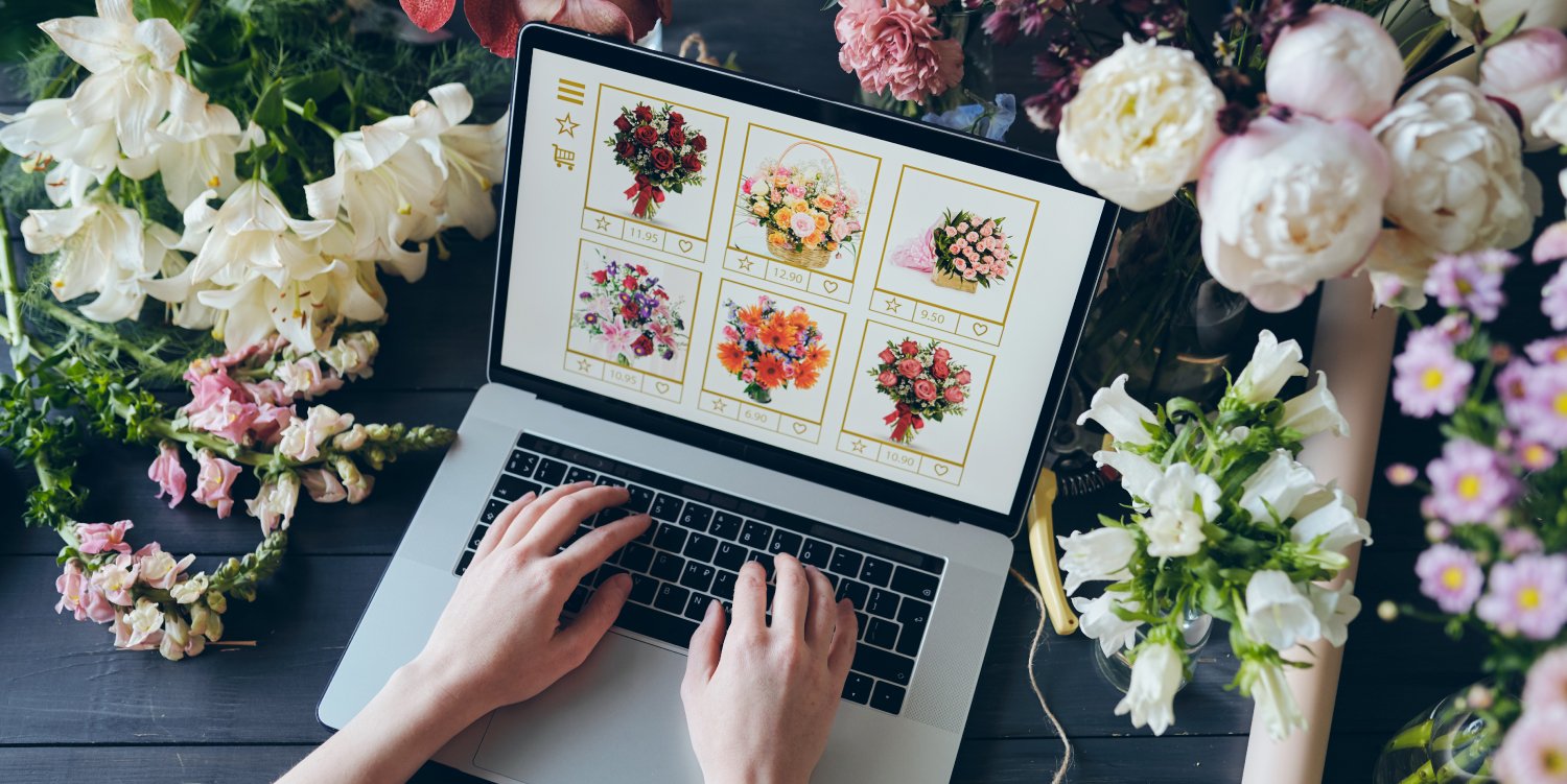 Hands typing on a laptop surrounded by flowers on an ecommerce website